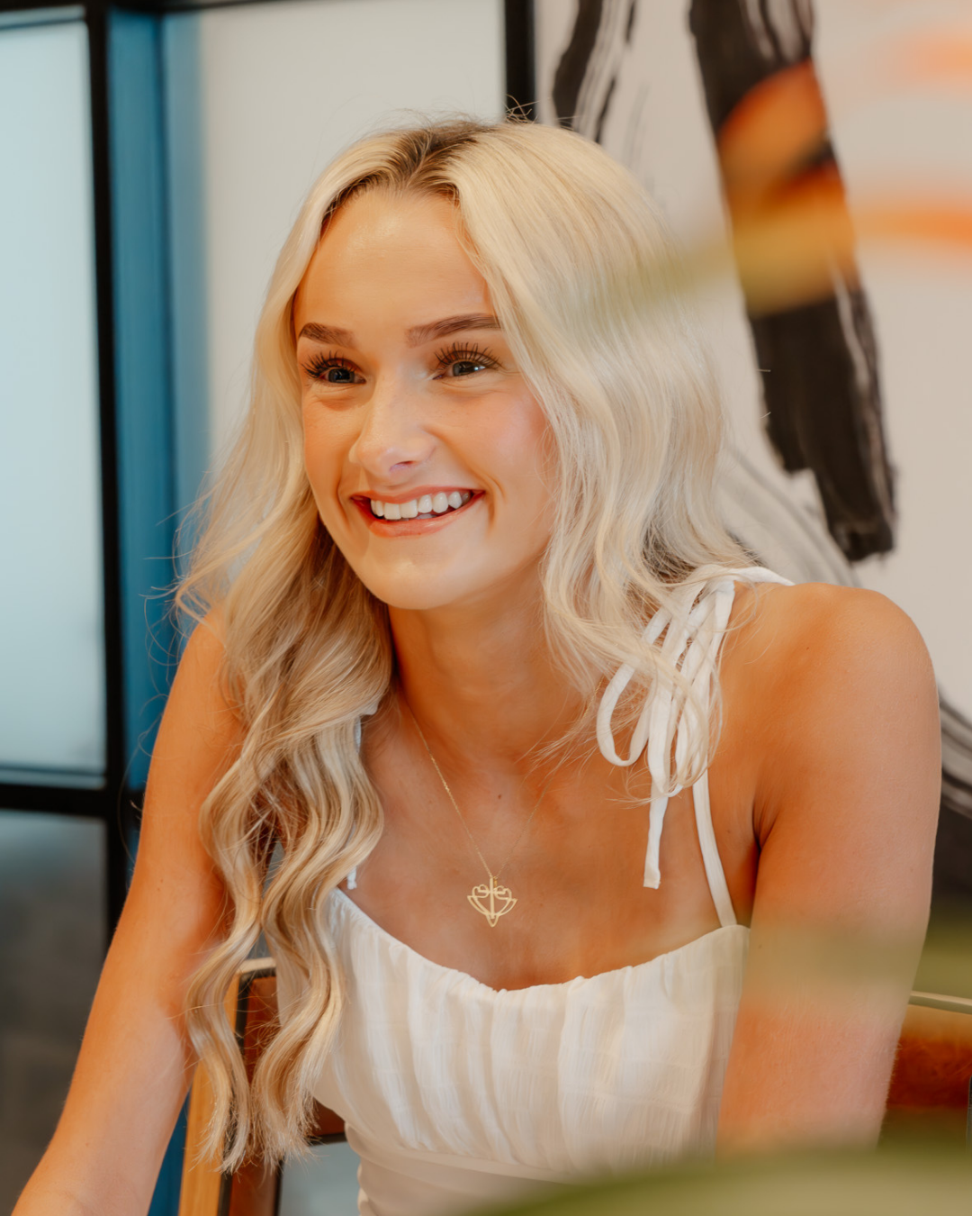 Smiling woman wearing a minimalist gold necklace with a unique pendant, reflecting 2025 jewelry style trends.